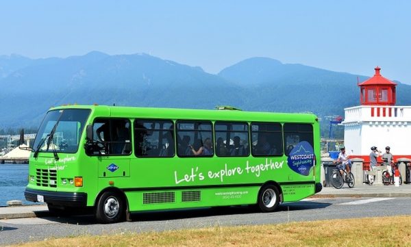 Sightseeing bus next to the ocean with attendees inside.